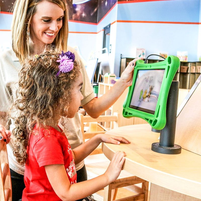 Teacher helping preschool-aged girl